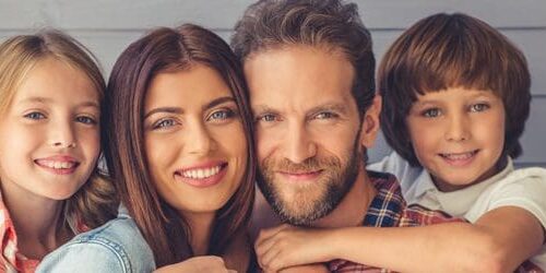 A man and woman smiling for the camera with two children.