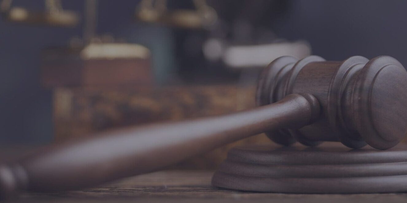 A judge ‘s gavel sitting on top of a wooden table. A judge 's gavel sitting on top of a wooden table.